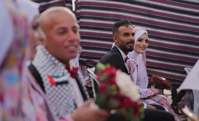 Palestinian bride Ola Al-Sharif looks at the camera as she participates with her groom, Mohamed al-sharif, in a mass wedding ceremony in Deir al-Balah, central Gaza Strip, Friday, April 24, 2026. (AP Photo/Abdel Kareem Hana)