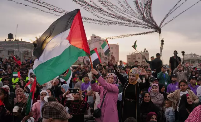 A woman waves a Palestinian flag as she watches a mass wedding ceremony in Deir al-Balah, central Gaza Strip, Friday, April 24, 2026. (AP Photo/Abdel Kareem Hana)