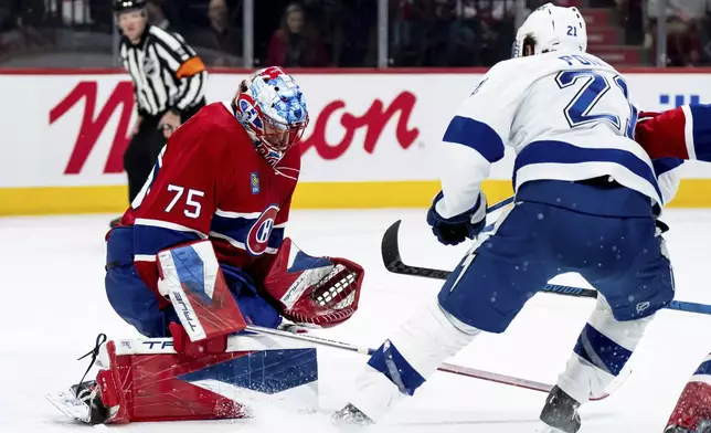 Montreal Canadiens goaltender Jakub Dobes (75) makes a save against Tampa Bay Lightning' Brayden Point (21) during the second period of an NHL hockey game in Montreal on Thursday, April 9, 2026. (Christopher Katsarov/The Canadian Press via AP)