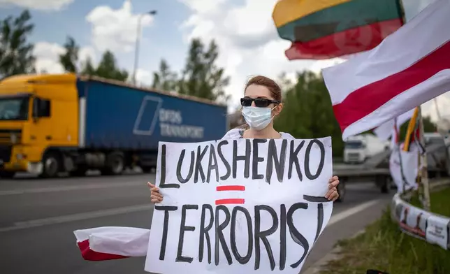 FILE - A protester holds a banner, old Belarusian and Lithuanian national flags during a protest demanding freedom for political prisoners in Belarus near Medininkai, Lithuanian-Belarusian border crossing point east of Vilnius, Lithuania, Tuesday, June 8, 2021. (AP Photo/Mindaugas Kulbis, File)