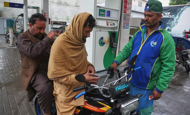A motorcyclist buys fuel after the government increased fuel prices amid surging global oil prices due to the Iran war, in Peshawar, Pakistan, Friday, April 3, 2026. (AP Photo/Muhammad Sajjad)
