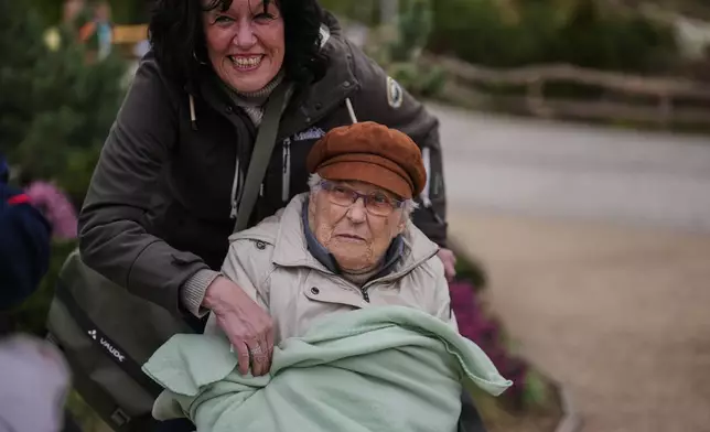 Ingrid Barkow, left, is wrapped in a blanket by her daughter Manuela Grudda, during a guided tour for people with dementia organized by Malteser Deutschland, part of the international Catholic aid organization Malteser Order of Malta, at the Zoo in Berlin, Germany, Thursday, March 26, 2026. (AP Photo/Markus Schreiber)