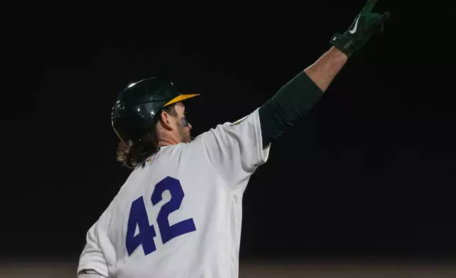 Athletics' Jacob Wilson gestures to the bullpen after hitting a two-run home run during the seventh inning of a baseball game against the Texas Rangers, Wednesday, April 15, 2026, in West Sacramento, Calif. (AP Photo/Scott Marshall)