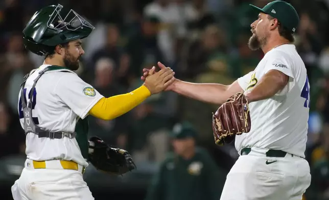 Athletics pitcher Joel Kuhnel, right, shakes hands with Shea Langeliers after the Athletics victory over the Texas Rangers in a baseball game Wednesday, April 15, 2026, in West Sacramento, Calif. (AP Photo/Scott Marshall)