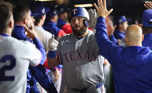 Texas Rangers' Jake Burger, middle, celebrates with teammates after hitting a three-run home run during the eighth inning of a baseball game against the Athletics, Wednesday, April 15, 2026, in West Sacramento, Calif. (AP Photo/Scott Marshall)