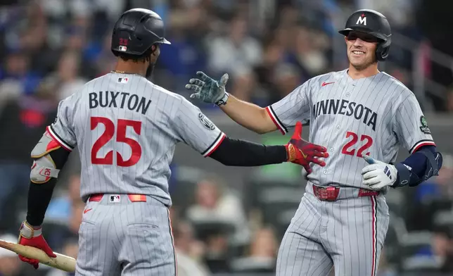 Minnesota Twins' Brooks Lee (22) celebrates his hits a solo home run with Byron Buxton during the third inning of a baseball action against the Toronto Blue Jays in Toronto, Saturday, April 11, 2026. (Nathan Denette/The Canadian Press via AP)