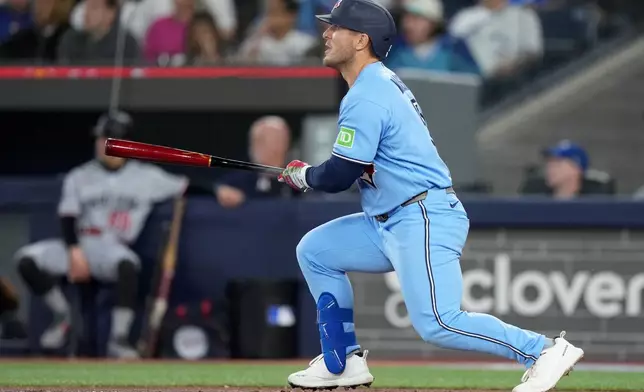 Toronto Blue Jays' Daulton Varsho (5) watches the ball as he hits a two-run home run against the Minnesota Twins during the first inning of a baseball game in Toronto, Saturday, April 11, 2026. (Nathan Denette/The Canadian Press via AP)