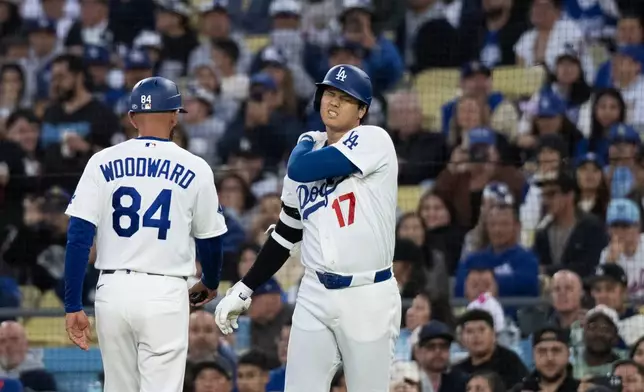 Los Angeles Dodgers' Shohei Ohtani, right, reacts after taking a hit by a pitch during the first inning of a baseball game against the New York Mets in Los Angeles, Monday, April 13, 2026. (AP Photo/Kyusung Gong)