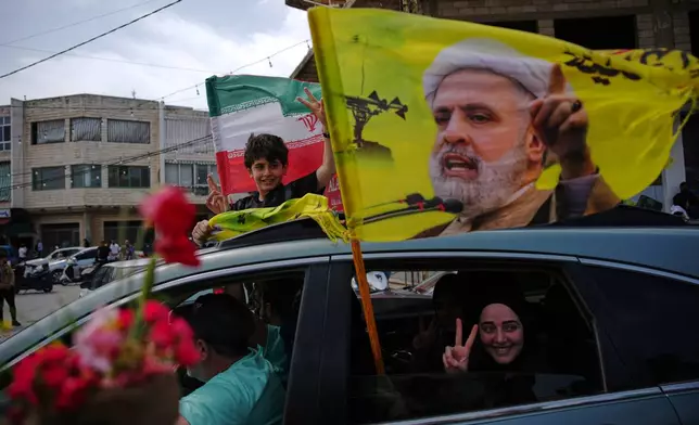 Displaced residents wave a flag with the image of Hezbollah leader Naim Qassem as they return to their villages following a ceasefire between Israel and Hezbollah, in Zefta, southern Lebanon, Friday, April 17, 2026. (AP Photo/Hassan Ammar)