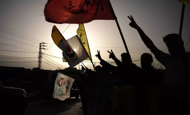 People wave Hezbollah flags and an image of late Hezbollah leader Hassan Nasrallah, in Zefta, southern Lebanon, Friday, April 17, 2026, as displaced residents drive back to their villages following a ceasefire between Israel and Hezbollah. (AP Photo/Hassan Ammar)