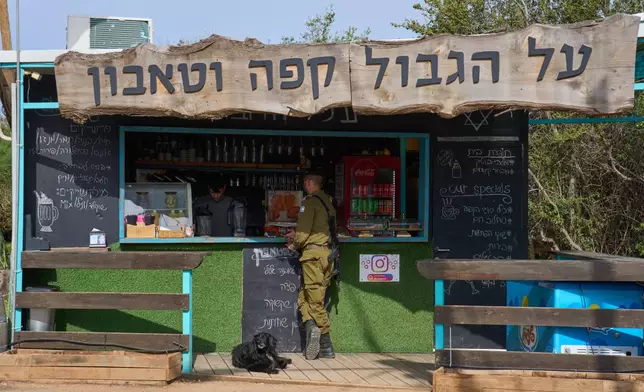 An Israeli soldier orders drinks from a coffee shop in northern Israel, on the border with Lebanon following a ceasefire between Israel and Hezbollah, Friday, April 17, 2026. Signage in Hebrew reads, "Coffee on the border."(AP Photo/Ariel Schalit)