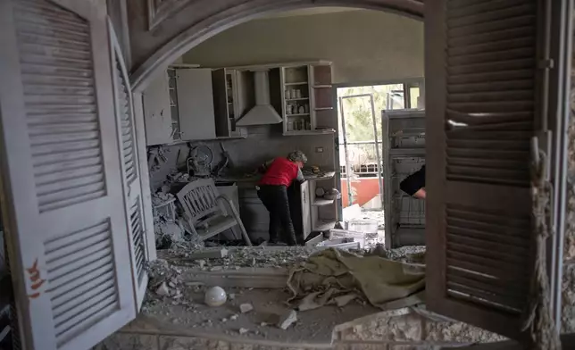 A woman, no name given, enters her house heavily damaged in a Israeli airstrike in Kfar Roumman, southern Lebanon, Friday, April 17, 2026, following a ceasefire between Israel and Hezbollah. (AP Photo/Hassan Ammar)