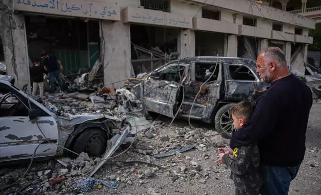 Locals residents stand among debris and vehicles destroyed in an Israeli airstrike in Jibchit, southern Lebanon, Friday, April 17, 2026, following a ceasefire between Israel and Hezbollah. (AP Photo/Hassan Ammar)