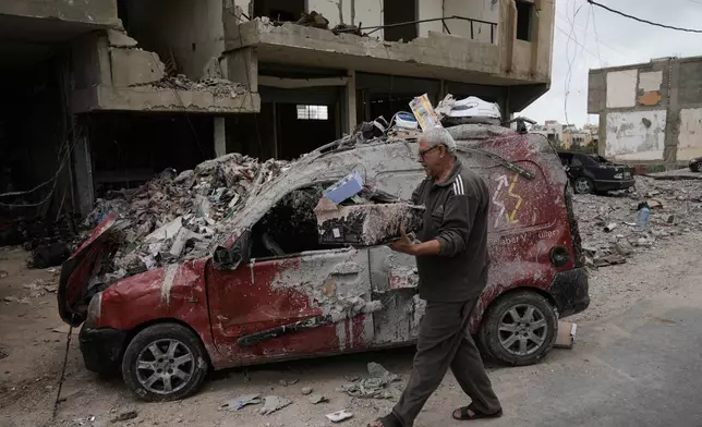 Mahmoud Ghadboun retrieves some of his belongings from a building destroyed in a previous Israeli airstrike, during a ceasefire between Hezbollah and Israel in the Hosh neighborhood of Tyre, southern Lebanon, on Sunday, April 19, 2026. (AP Photo/Bilal Hussein)