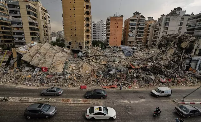 Residents drive past the rubble of destroyed buildings in Dahiyeh, Beirut's southern suburbs, Lebanon, Friday, April 17, 2026, following a ceasefire between Israel and Hezbollah. (AP Photo/Bilal Hussein)