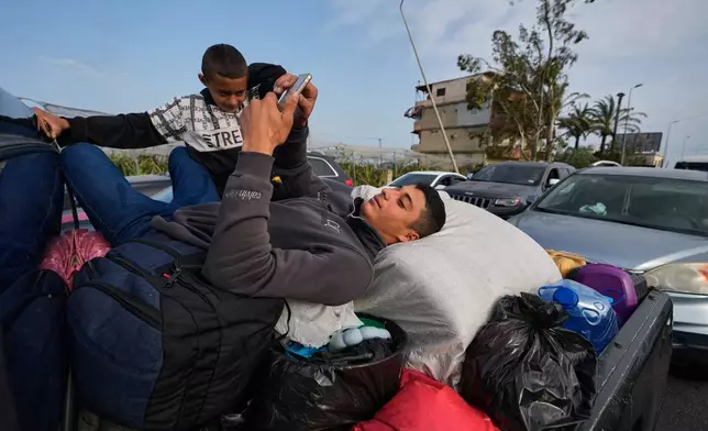 A displaced man lies over belongings on a mini pickup and checks his mobile phone, in Qasmiyeh near Tyre city, south Lebanon, as he returns with his family to their village following a ceasefire between Hezbollah and Israel, Friday, April 17, 2026. (AP Photo/Mohammed Zaatari)
