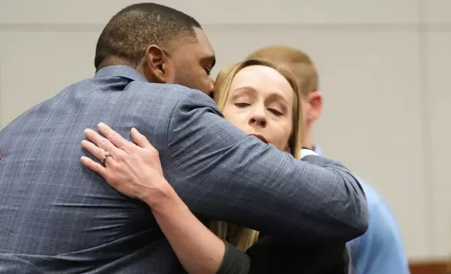 Former Michigan football coach Sherrone Moore hugs his wife wife Kelli Moore in court Tuesday, April 14, 2026, in Ann Arbor, Mich. (AP Photo/Paul Sancya)
