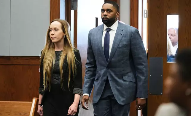 Former Michigan football coach Sherrone Moore arrives in court with with his wife Kelli Moore, Tuesday, April 14, 2026, in Ann Arbor, Mich. (AP Photo/Paul Sancya)