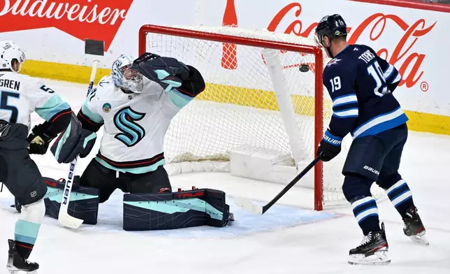 A shot by Winnipeg Jets' Kyle Connor (not shown) gets past Seattle Kraken goaltender Philipp Grubauer, second from right, for a goal as Jets' Jonathan Toews (19) looks for a rebound during second-period NHL hockey game action in Winnipeg, Manitoba, Monday, April 6, 2026. (Fred Greenslade/The Canadian Press via AP)