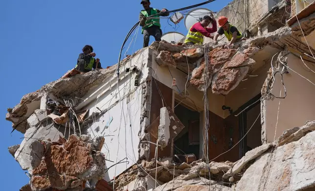 Workers remove the rubble as rescuers keep searching for a missing woman and girl at a destroyed building that was hit on April 8, in an Israeli airstrike in Beirut, Lebanon, Monday, April 13, 2026. (AP Photo/Hussein Malla)