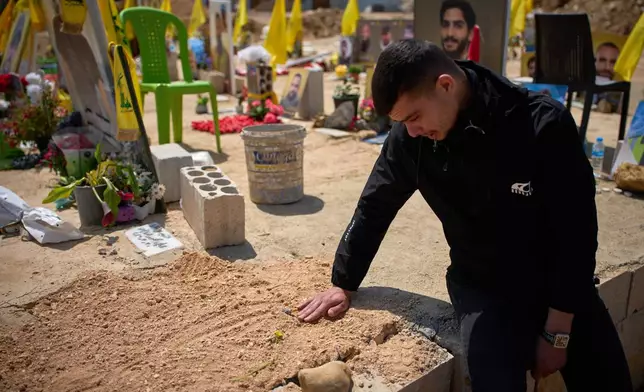 Ahmad Assi, 29, cries on the grave of his friend Hassan Ali Badawi, a paramedic of the Lebanese Red Cross killed in a Israeli strike, during his funeral in Choueifat, Lebanon, Monday, April 13, 2026. (AP Photo/Emilio Morenatti)