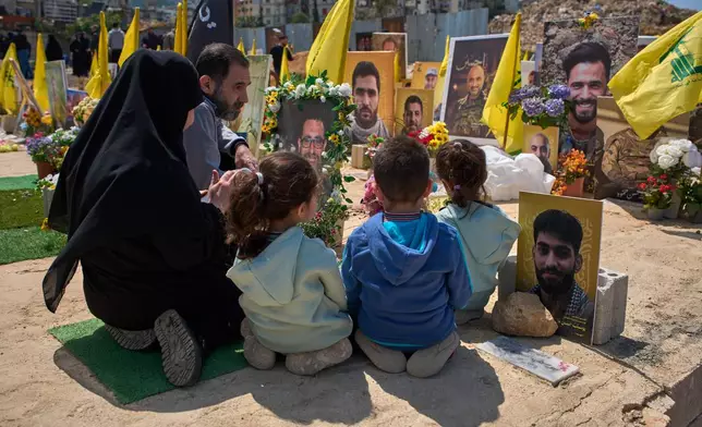 Family members pray at the grave of a relative buried alongside Hezbollah fighters killed in Israeli strikes, in a cemetery in Choueifat, Lebanon, Monday, April 13, 2026. (AP Photo/Emilio Morenatti)