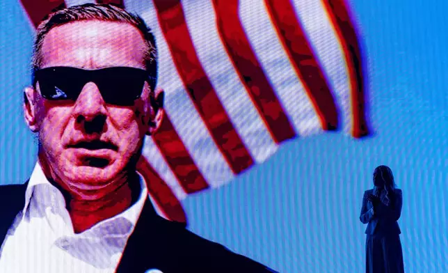 Erika Kirk stands as a video of the assassination attempt of President Donald Trump plays behind her at a Turning Point USA event at Dream City Church, Friday, April 17, 2026, in Phoenix. (AP Photo/Alex Brandon)