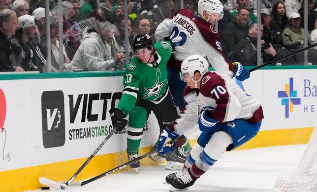 Dallas Stars center Oskar Bäck (10) is slammed against the boards by Colorado Avalanche's Gabriel Landeskog (92) as Sam Malinski (70) takes control of the puck in the first period of an NHL hockey game Saturday, April 4, 2026, in Dallas. (AP Photo/Tony Gutierrez)