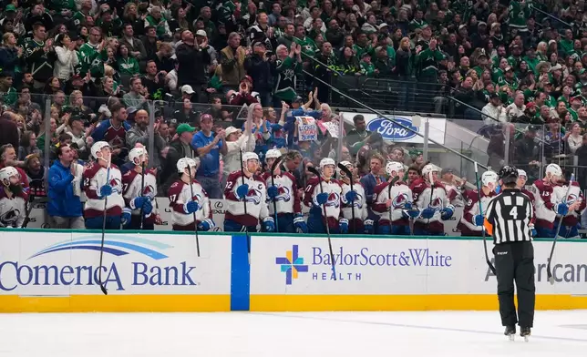 Fans and the Colorado Avalanche cheer after an in-house announcement celebrating Brent Burns', left sitting on bench, 1000th career game achievement in the first period of an NHL hockey game against the Dallas Stars, Saturday, April 4, 2026, in Dallas. (AP Photo/Tony Gutierrez)