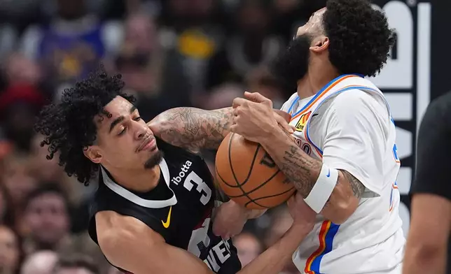 Denver Nuggets guard Julian Strawther, left, fights for control of the ball with Oklahoma City Thunder forward Kenrich Williams, right, in the first half of an NBA basketball game Friday, April 10, 2026, in Denver. (AP Photo/David Zalubowski)