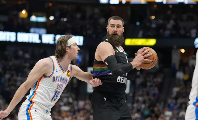 Denver Nuggets center Jonas Valančiūnas, right, looks to pass the ball as Oklahoma City Thunder center Branden Carlson defends in the first half of an NBA basketball game Friday, April 10, 2026, in Denver. (AP Photo/David Zalubowski)