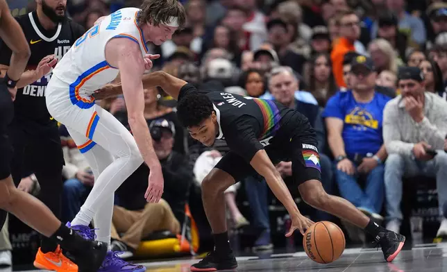 Denver Nuggets guard Curtis Jones, right, collects a loose ball as Oklahoma City Thunder center Branden Carlson covers in the first half of an NBA basketball game Friday, April 10, 2026, in Denver. (AP Photo/David Zalubowski)