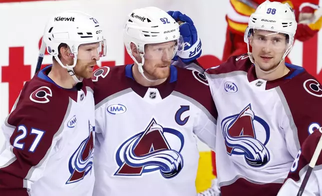 Colorado Avalanche's Gabriel Landeskog, center, celebrates his goal against the Calgary Flames with Brett Kulak, left, and Martin Necas during the third period of an NHL hockey game in Calgary, Alberta, Tuesday, April 14, 2026. (Larry MacDougal/The Canadian Press via AP)