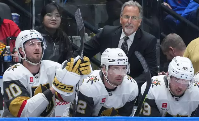 Vegas Golden Knights head coach John Tortorella, back right, stands on the bench behind Colton Sissons, left to right, Cole Smith and Ivan Barbashev during the second period of an NHL hockey game against the Vancouver Canucks, in Vancouver, on Tuesday, April 7, 2026. (Darryl Dyck/The Canadian Press via AP)