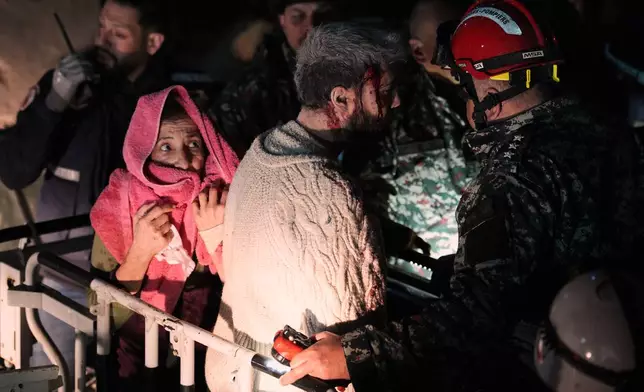 A woman and an injured man, center, are rescued by firefighters from a destroyed building that was hit in an Israeli airstrike in central Beirut, Lebanon, Wednesday, April 8, 2026. (AP Photo/Emilio Morenatti)