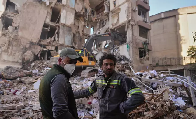 A Lebanese civil defense worker, right, stands with a resident at the site of a building destroyed in an Israeli airstrike a day earlier in central Beirut, Lebanon, Thursday, April 9, 2026. (AP Photo/Hassan Ammar)