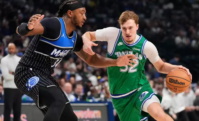 Dallas Mavericks forward Cooper Flagg (32) drives to the basket as Orlando Magic's Wendell Carter Jr. (34) defends in the first half of an NBA basketball game Friday, April 3, 2026, in Dallas. (AP Photo/Tony Gutierrez)