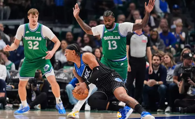 Orlando Magic forward Paolo Banchero, bottom, loses his footing as he works against Dallas Mavericks' Naji Marshall (13) in the first half of an NBA basketball game Friday, April 3, 2026, in Dallas. (AP Photo/Tony Gutierrez)