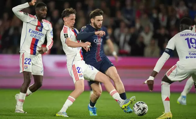 PSG's Khvicha Kvaratskhelia, centre right, and Lyon's Thiago Almada challenge for the ball during the French League One soccer match between Paris Saint-Germain and Olympique Lyon in Paris, France, Sunday, April 19, 2026. (AP Photo/Christophe Ena)