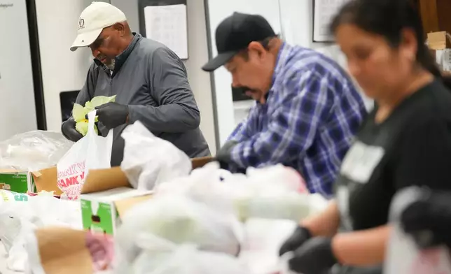 Lawrence Hall, left, a volunteer at Miles of Freedom, a Dallas-based group that provides help for individuals after they have been released from prison, whether they are on parole or are exonerees, fills grocery bags at the organization's soup kitchen Tuesday, April 21, 2026 in Dallas. (AP Photo/Julio Cortez)
