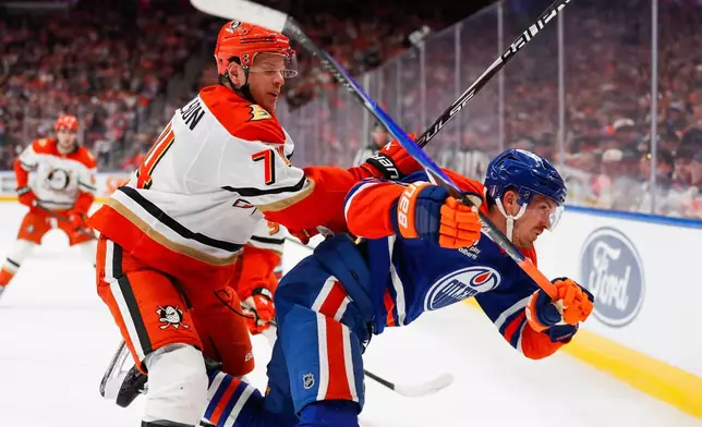 Anaheim Ducks' John Carlson (74) hits Edmonton Oilers' Jack Roslovic (28) during the second period of an NHL hockey playoff game in Edmonton, Alberta, on Wednesday, April 22, 2026. (Codie McLachlan/The Canadian Press via AP)