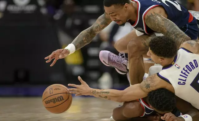 Los Angeles Clippers forward John Collins, top, and guard Bennedict Mathurin, bottom, battle for a loose ball with Sacramento Kings guard Nique Clifford during the second half of an NBA basketball game in Sacramento, Calif., Sunday, April 5, 2026. (AP Photo/Randall Benton)