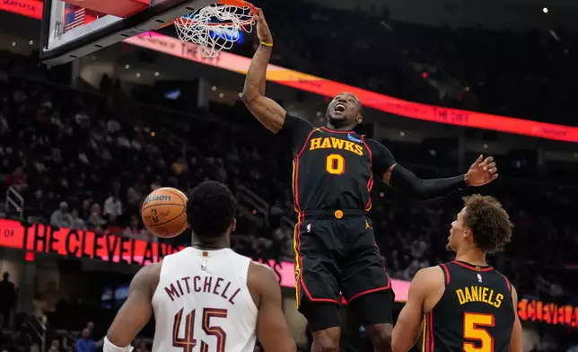 Atlanta Hawks forward Jonathan Kuminga (0) dunks in front of Cleveland Cavaliers guard Donovan Mitchell (45) and teammate Dyson Daniels (5) in the second half of an NBA basketball game in Cleveland, Wednesday, April 8, 2026. (AP Photo/Sue Ogrocki)