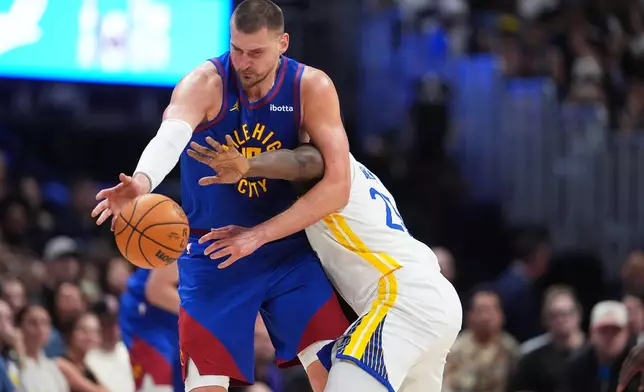 Denver Nuggets center Nikola Jokić, left, struggles to field a pass as Golden State Warriors forward Draymond Green defends in the second half of an NBA basketball game Sunday, March 29, 2026, in Denver. (AP Photo/David Zalubowski)