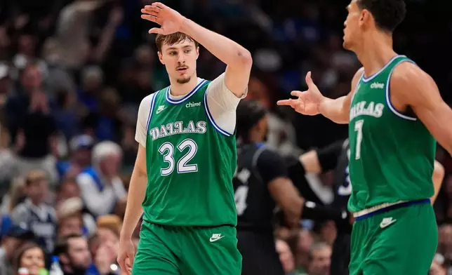Dallas Mavericks forward Cooper Flagg (32) and Dwight Powell, right, celebrate a basket by Flagg in the second half of an NBA basketball game against the Orlando Magic Friday, April 3, 2026, in Dallas. (AP Photo/Tony Gutierrez)