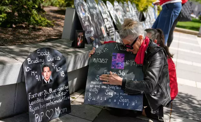 Tanny Austin cries while looking at tombstones with the names of victims of the opioid crisis, including her son Sean Austin, during a rally outside of a courthouse in Newark, N.J., Tuesday, April 21, 2026. (AP Photo/Seth Wenig)