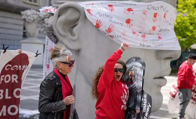 Stacy Schwab, center, and others react after hearing that a hearing for for Purdue Pharma had been rescheduled while relying outside a courthouse in Newark, N.J., Tuesday, April 21, 2026. (AP Photo/Seth Wenig)