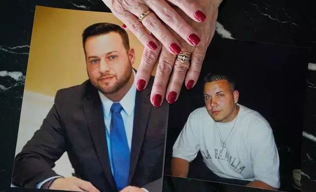 FILE - Cheryl Juaire holds photos of her sons, both of whom died from overdoses, Sean Merrill, left, and Corey Merrill, after making a statement during a hearing in New York on March 10, 2022. (AP Photo/Seth Wenig, File)