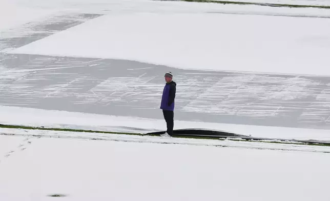 Mark Razum, head groundskeeper at Coors Field, surveys the covering of snow on the field after a spring storm blanketed the intermountain West before the Colorado Rockies host the Los Angeles Dodgers in a baseball game Friday, April 17, 2026, in Denver. (AP Photo/David Zalubowski)