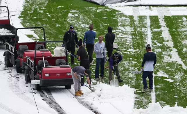 Grounds crew members toil to clear snow from the outfield of Coors Field after a spring storm blanketed the intermountain West before the Colorado Rockies host the Los Angeles Dodgers in a baseball game Friday, April 17, 2026, in Denver. (AP Photo/David Zalubowski)